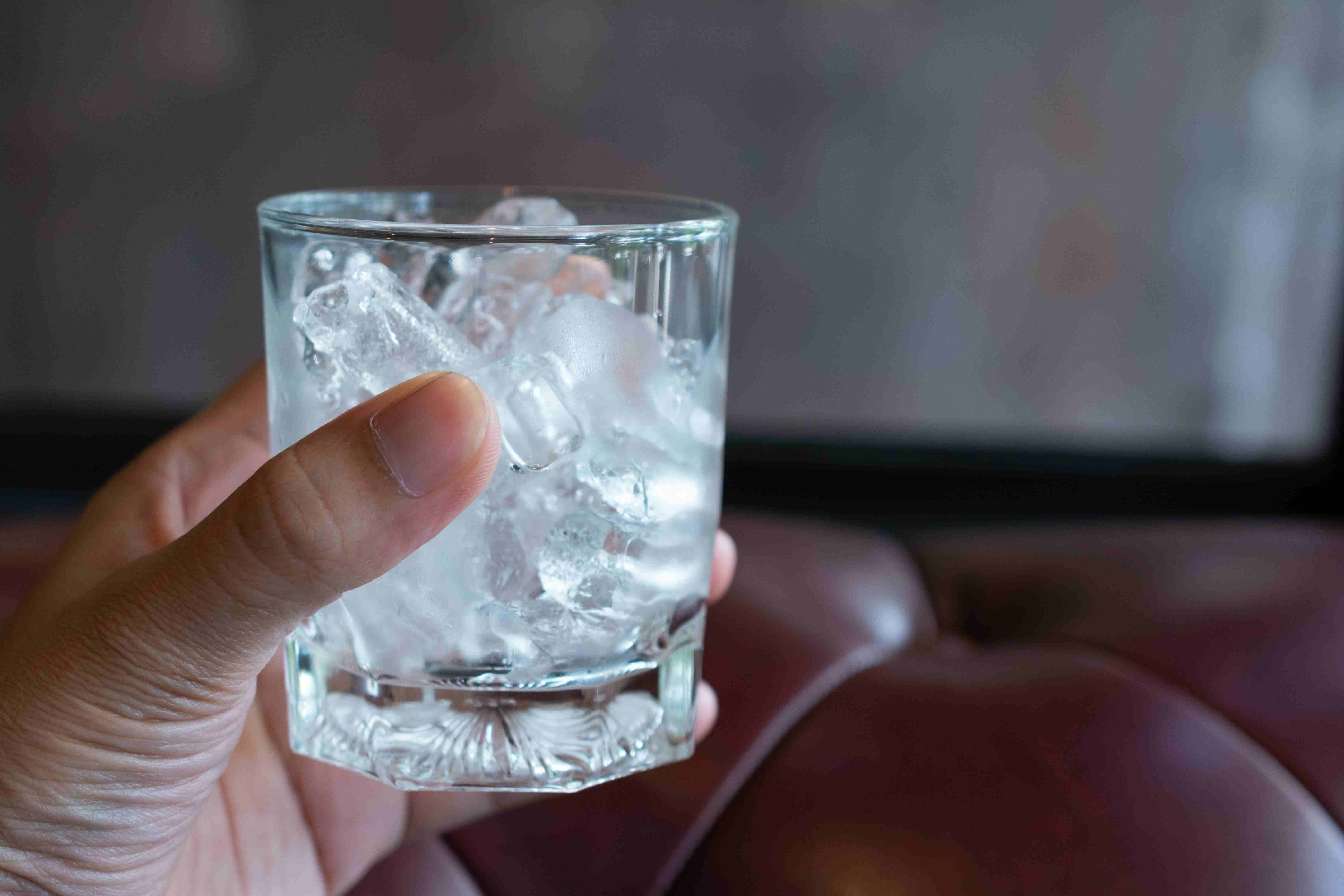 Hand holding a glass filled with ice cubes, illustrating a grounding technique for anxiety relief during pregnancy.