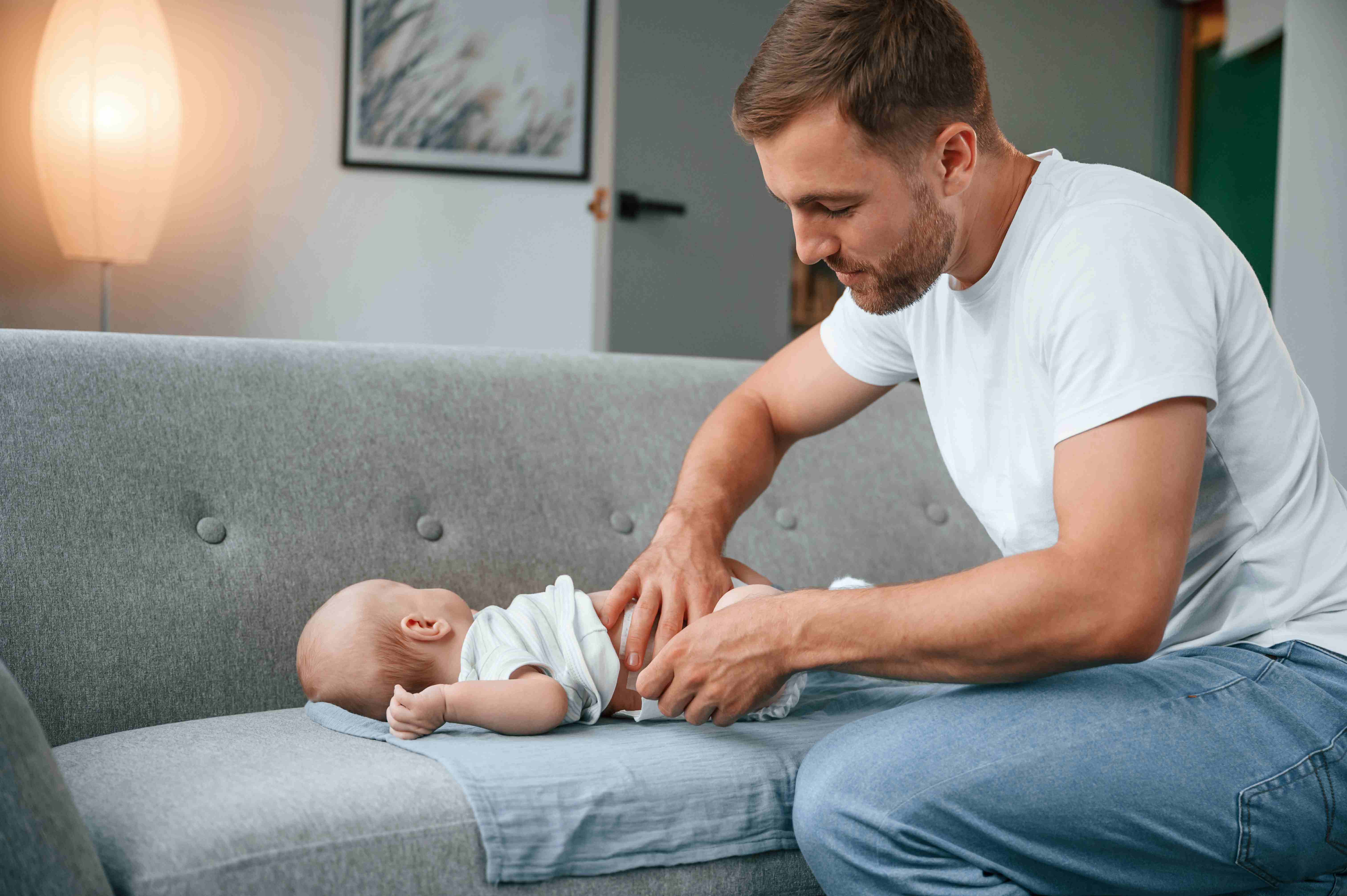 Father changing his baby’s diaper while bonding at home.