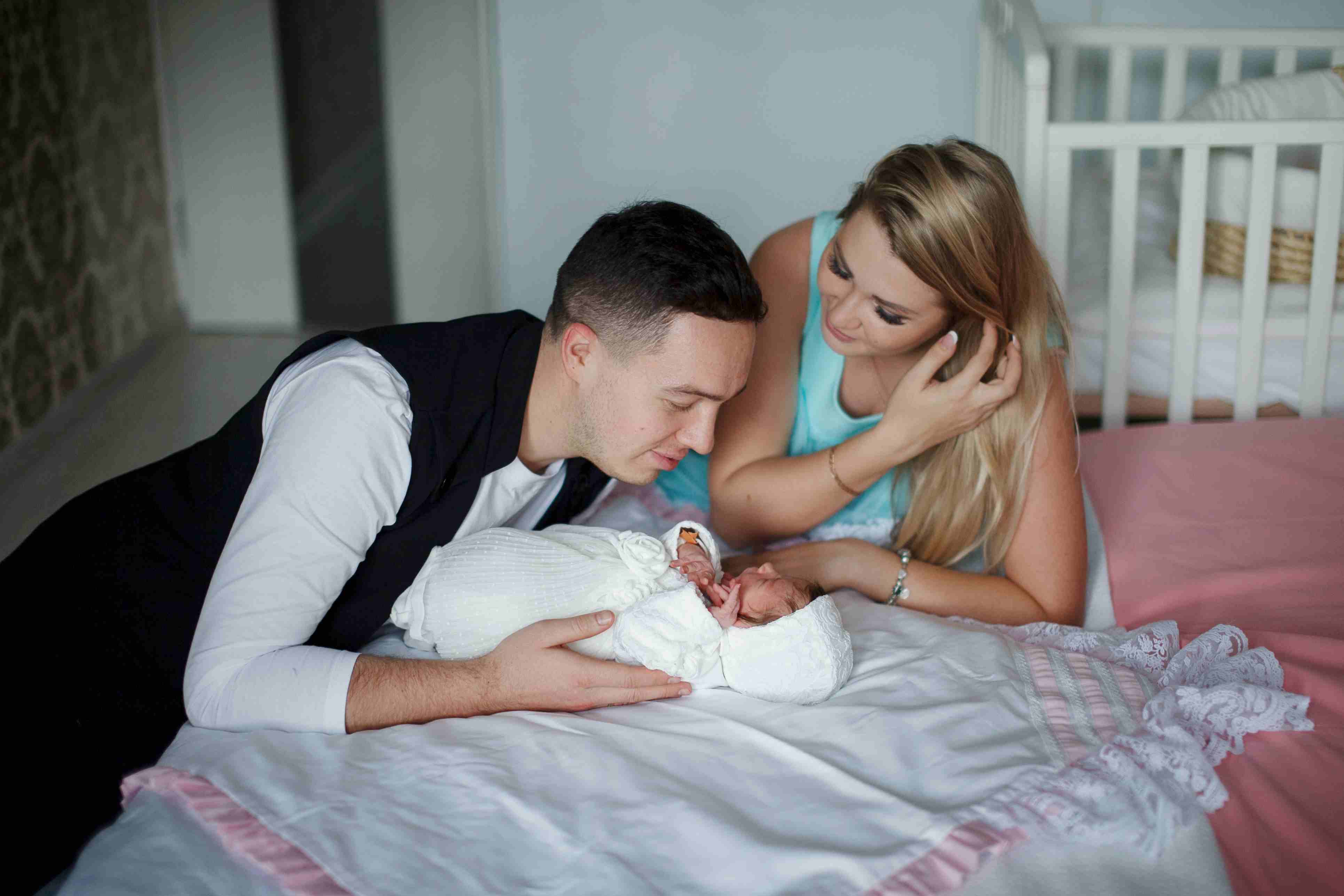 New parents smiling as they admire their newborn baby together.