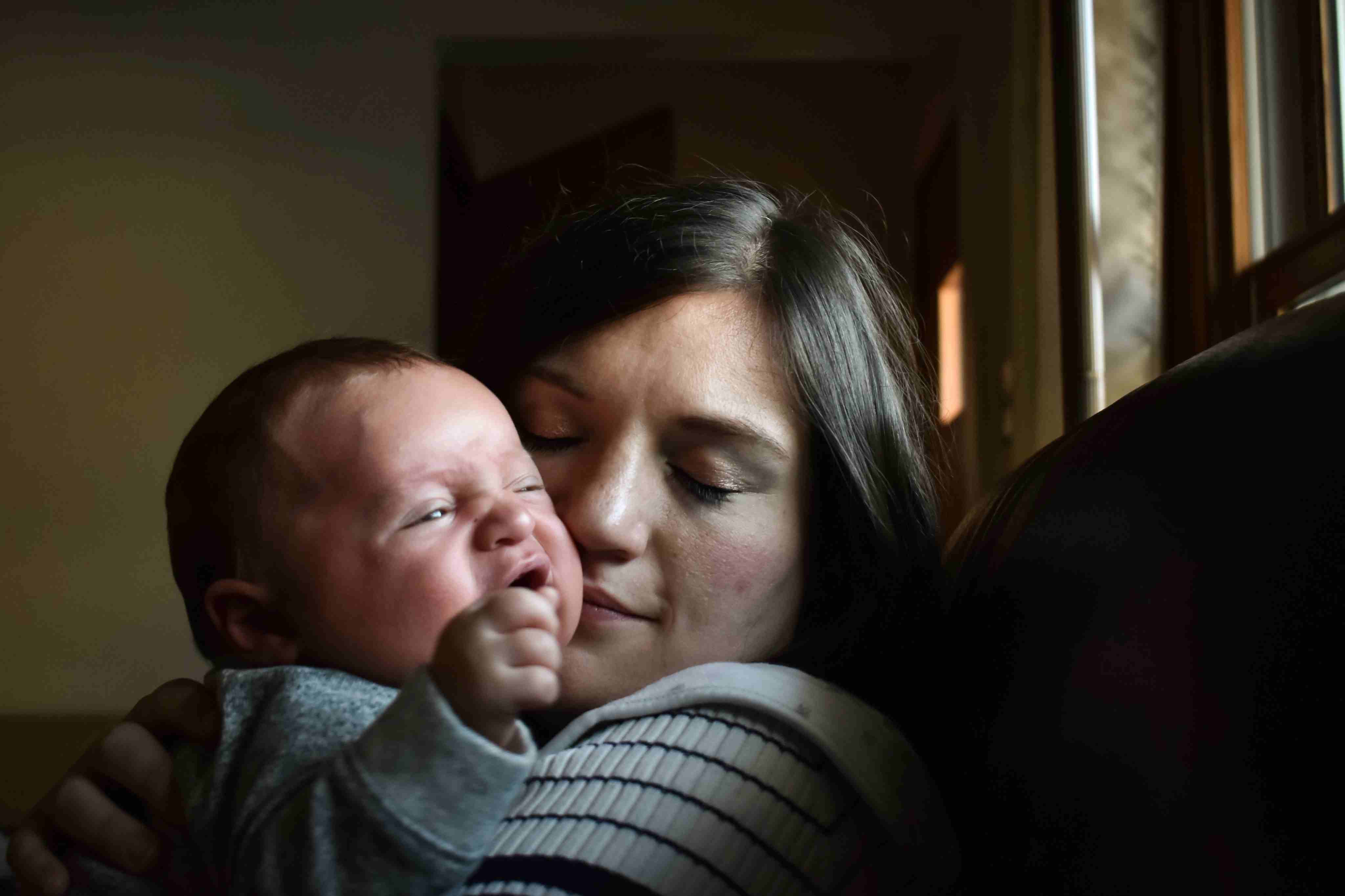 A mother who previously struggled with postpartum depression holds her baby close, showing how treatment has helped her reconnect emotionally and bond with her child again.